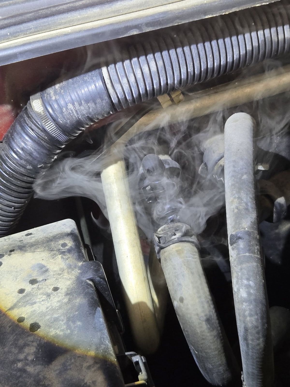 Smoke test on the cooling system of a 2006 Nissan Frontier in Ventura, smoke rising around the heater hoses
