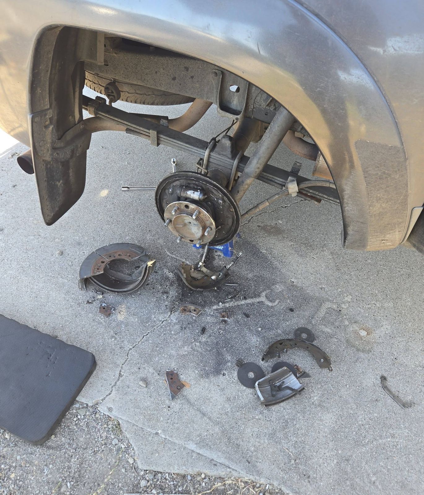 2011 Toyota Tacoma with the rear brake drum off and brake parts on the pavement