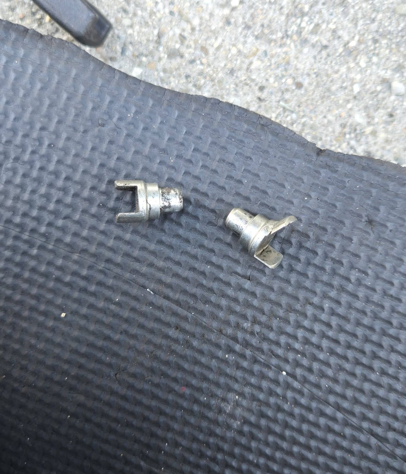 Two small metal parts removed during the 2011 Toyota Tacoma brake job, on a mat