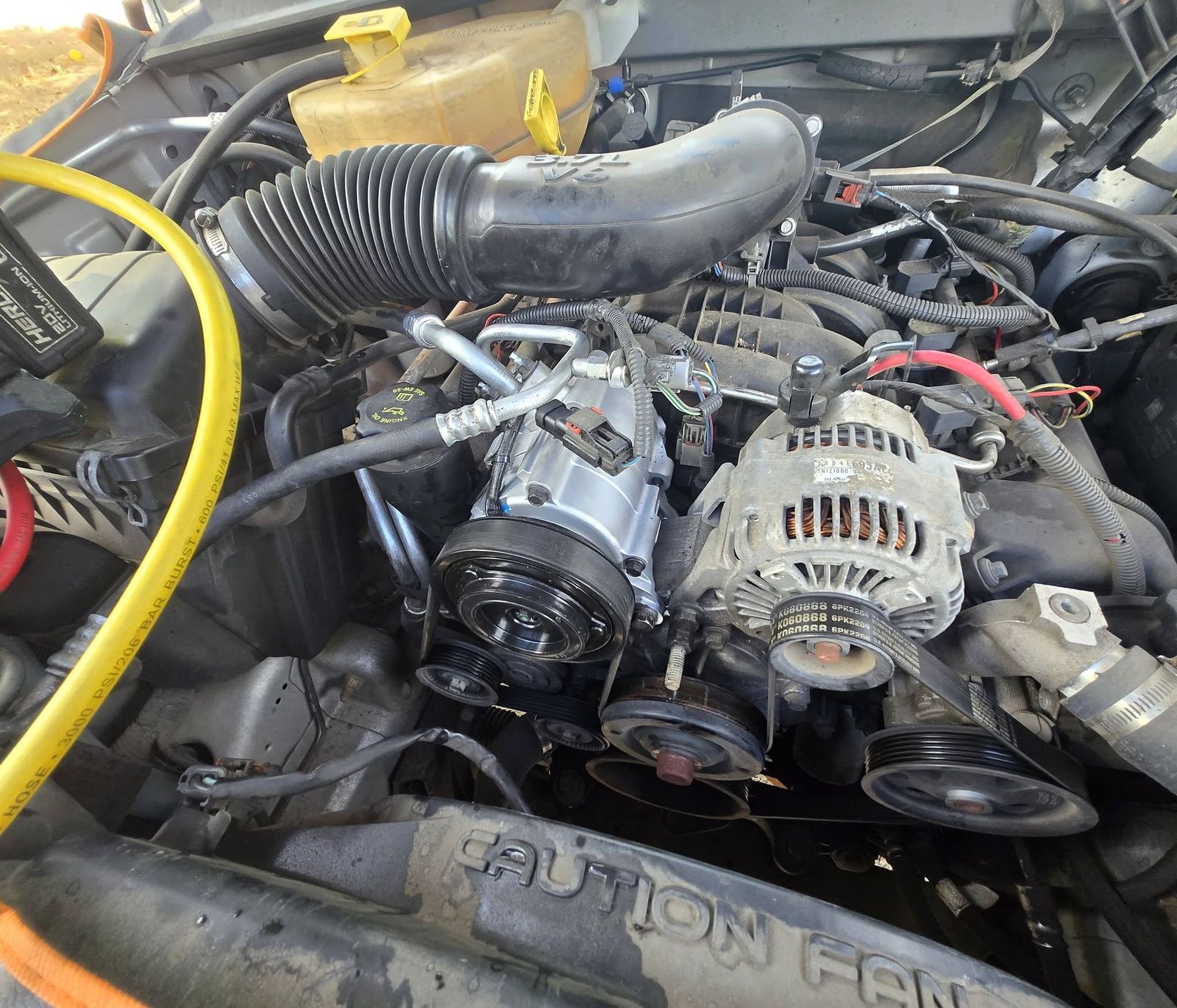 Engine bay with the A/C compressor and alternator, charging hose connected