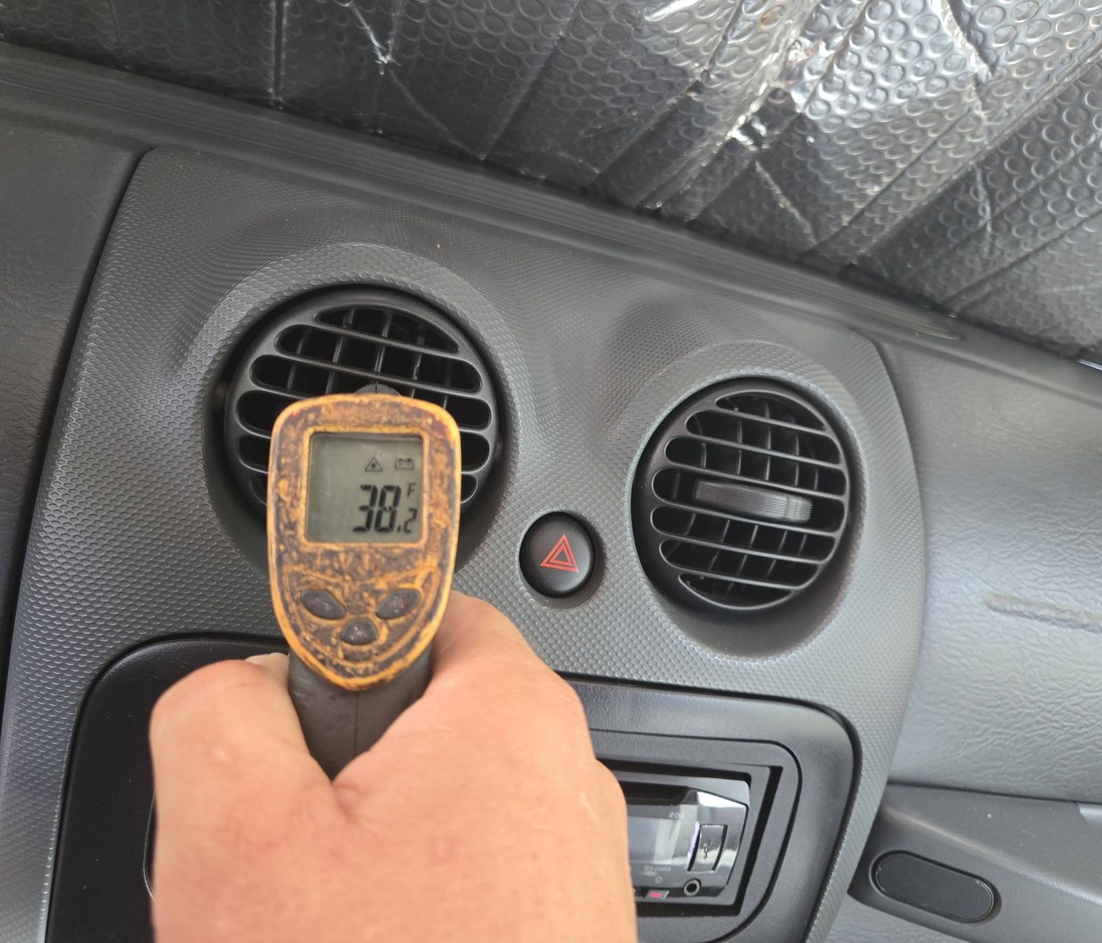Infrared thermometer reading the air temperature at a dashboard A/C vent