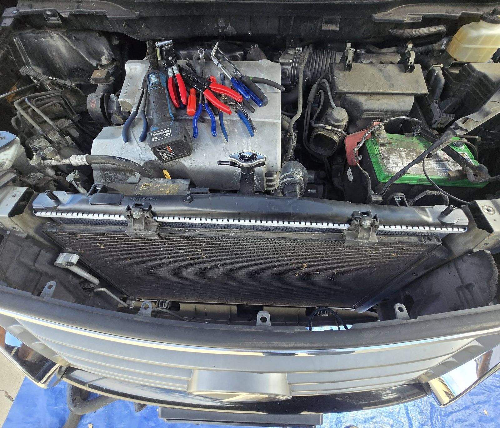 Front bumper cover removed with the radiator exposed and tools laid on the engine