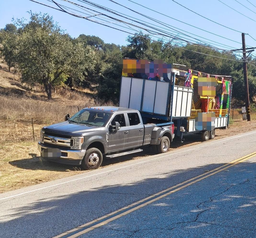 Ford pickup towing a trailer, parked on the shoulder of a rural road