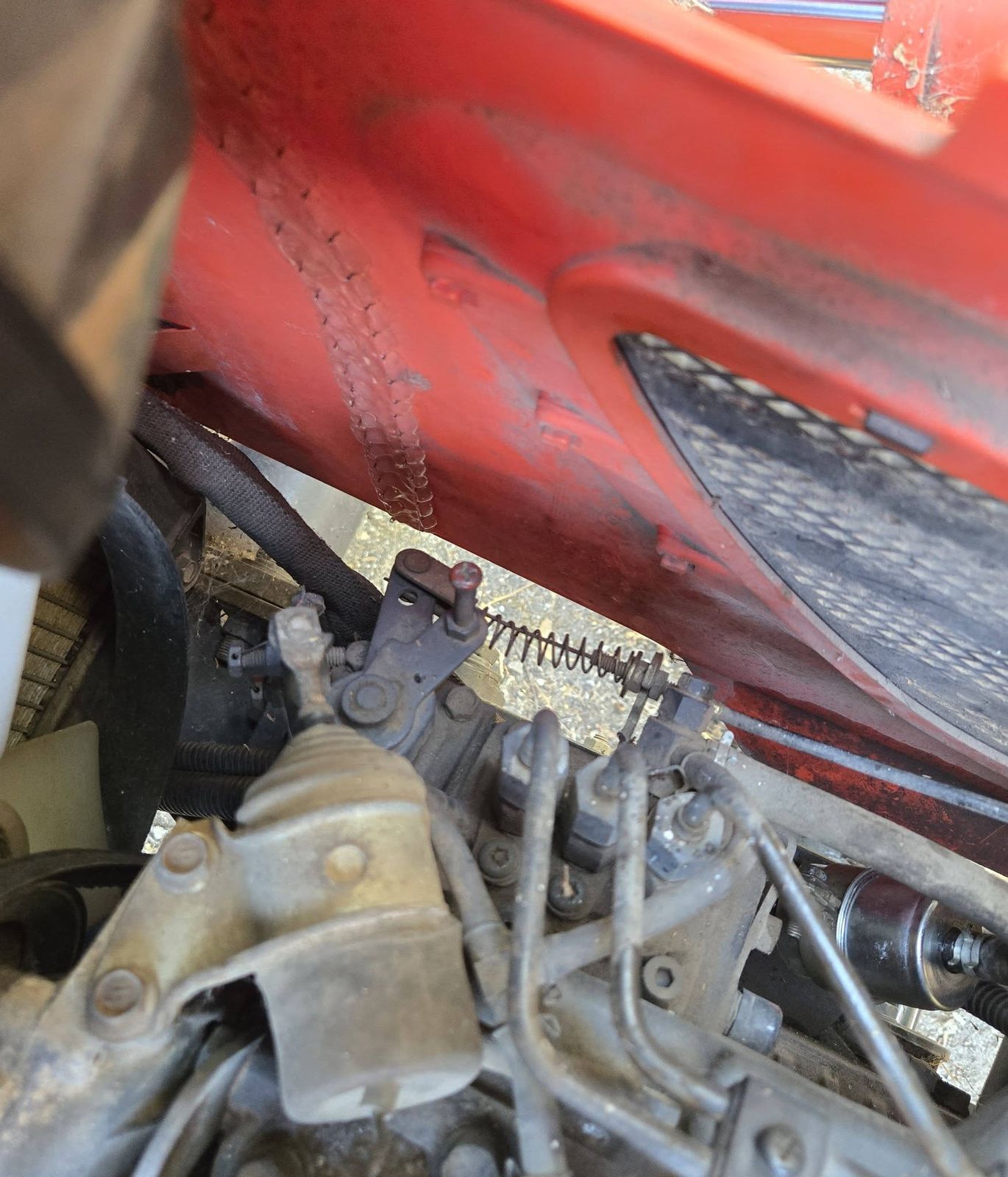 Compact tractor engine beside an orange hood panel with weld beads along it