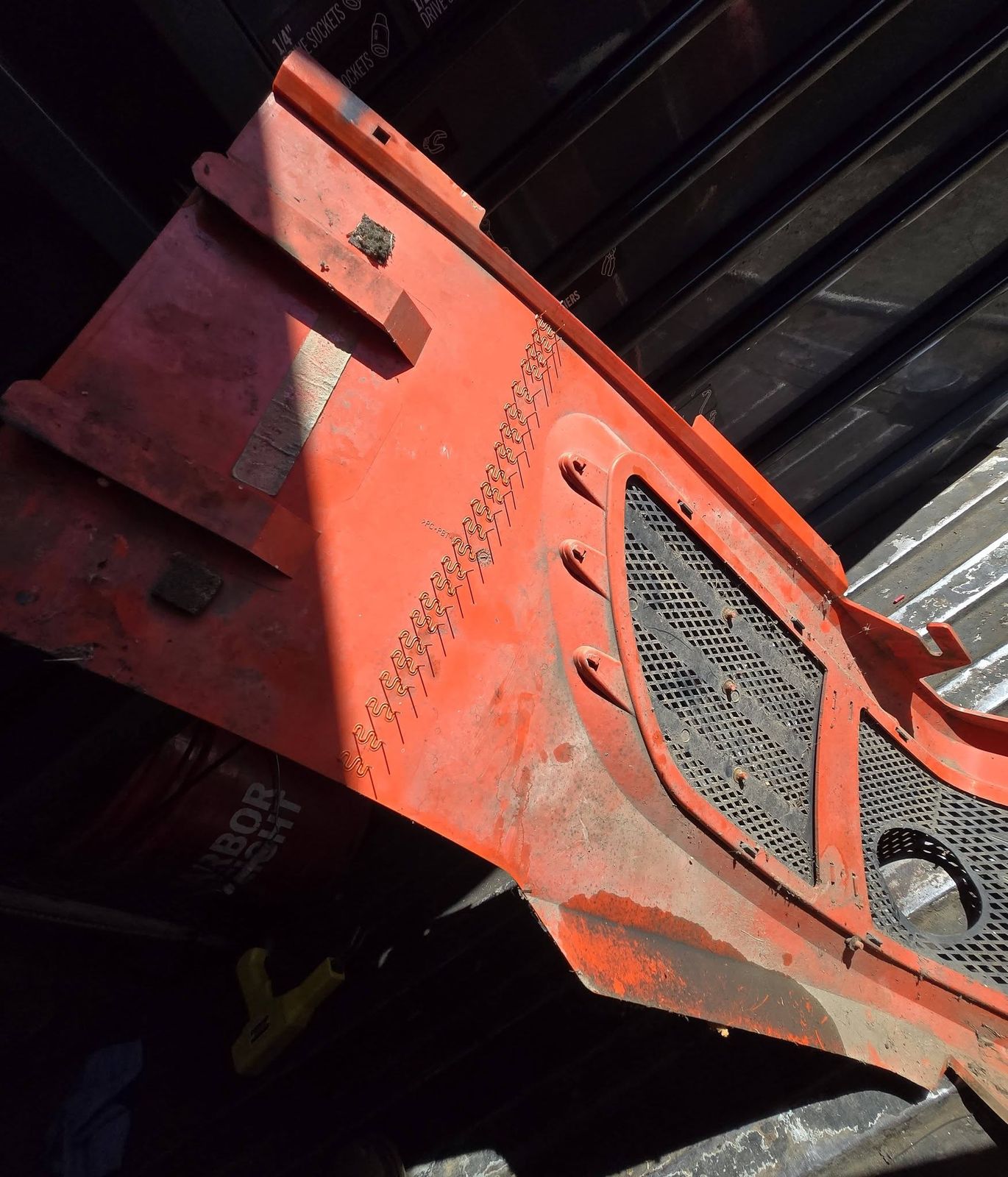 Orange tractor hood panel with welded seams and a grille